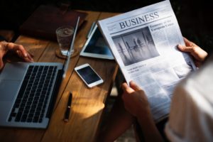 Person reading newspaper business section