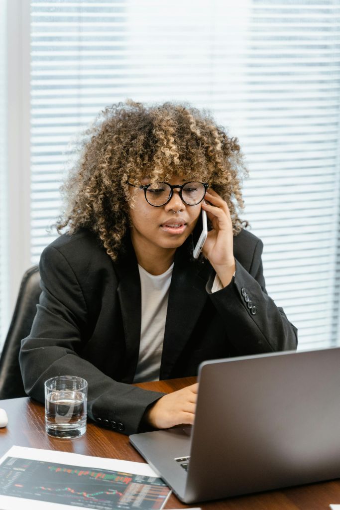 woman-using-laptop-while-on-a-phone-call